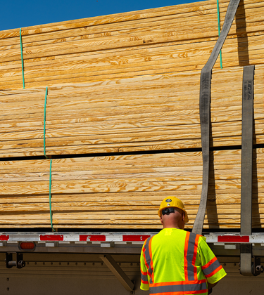 Man strapping lumber to truck